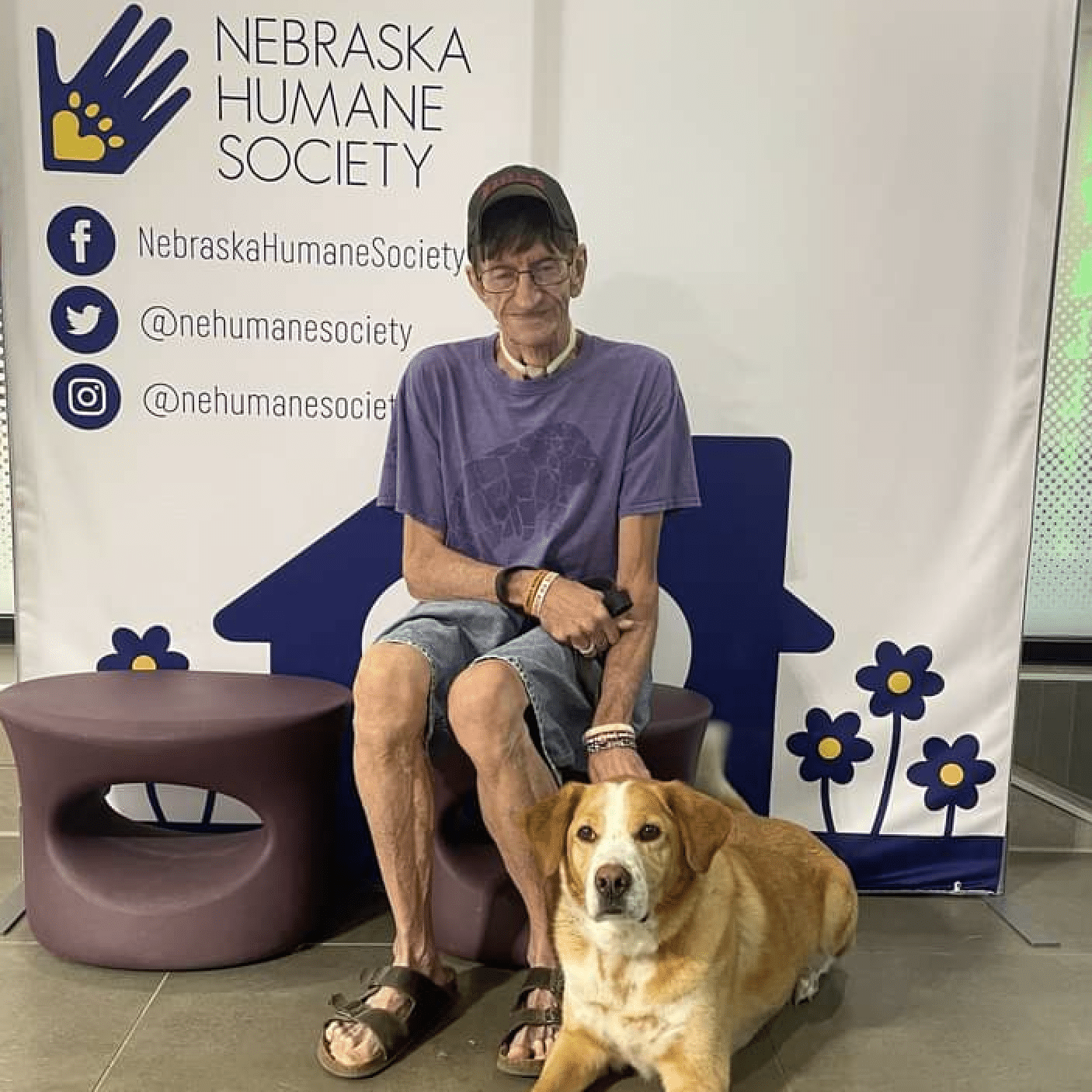 A man with his dog in front of an adoption banner